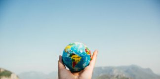 person holding world globe facing mountain